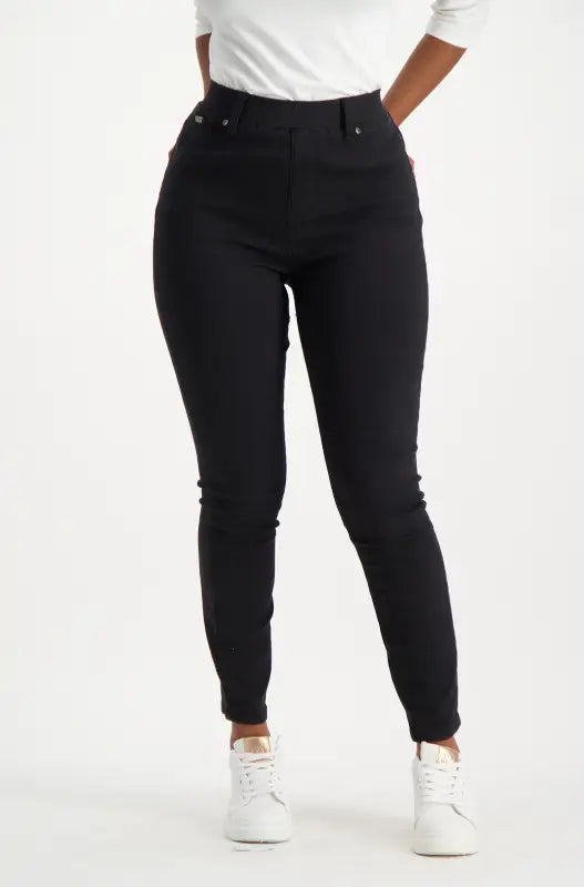 High-waisted black skinny jeans with white and gold sneakers.