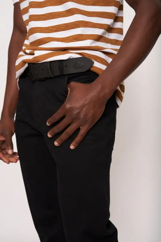Men’s black trousers with a dark brown and white striped t-shirt and a black belt.