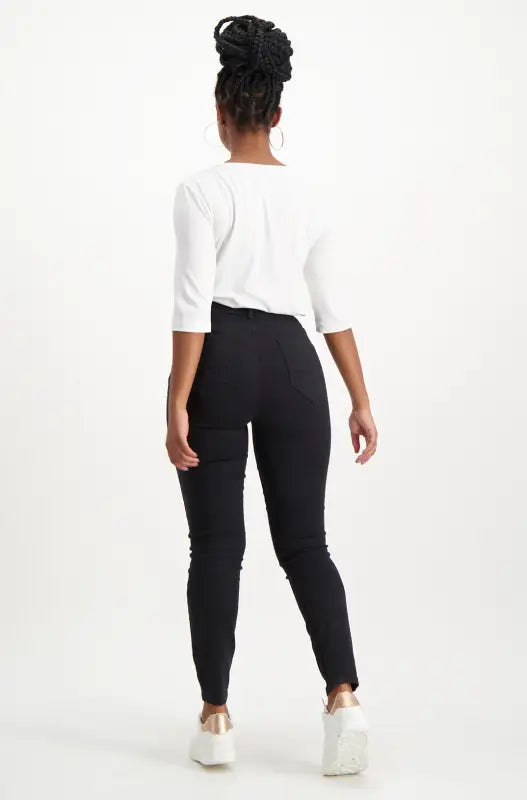 A woman’s white boat-neck top with three-quarter sleeves and black skinny pants.