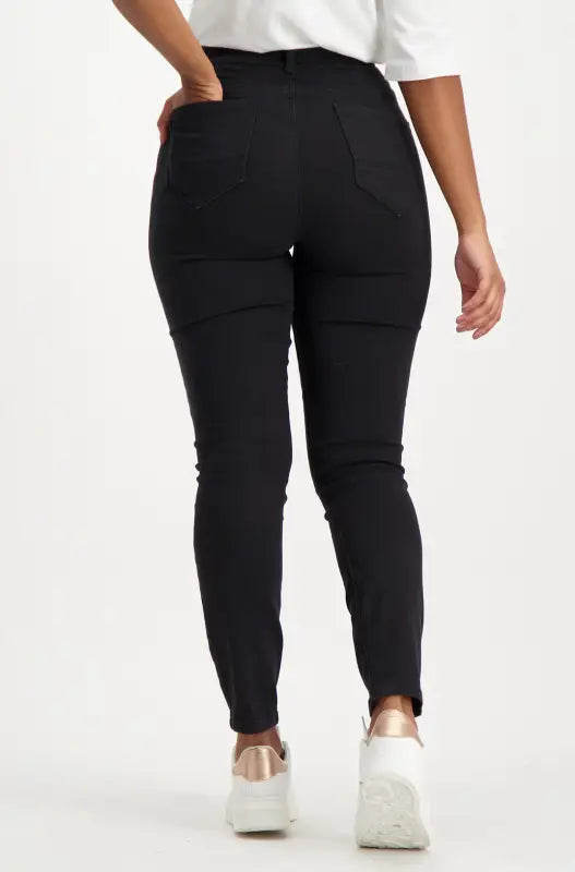 Women’s black skinny-fit pants with pockets, paired with white and rose gold sneakers.