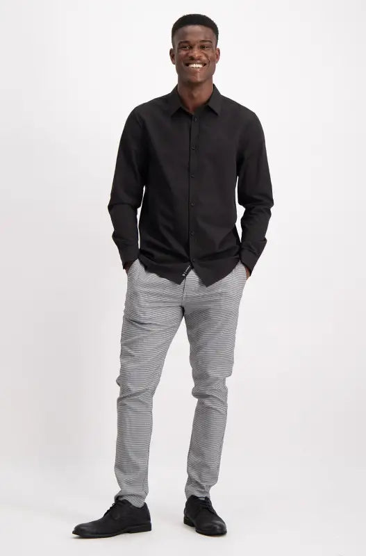 Men’s black long-sleeved button-down shirt with gray plaid pants and black dress shoes