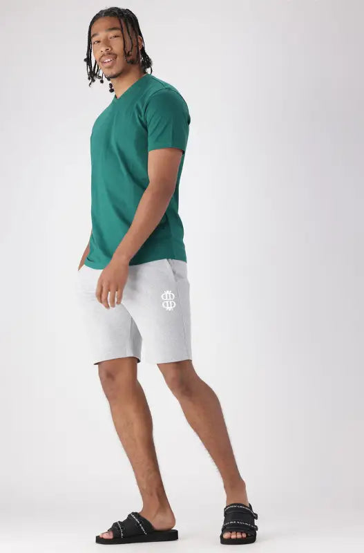 A men’s casual outfit consisting of a dark teal t-shirt, light gray shorts, and black slide sandals.