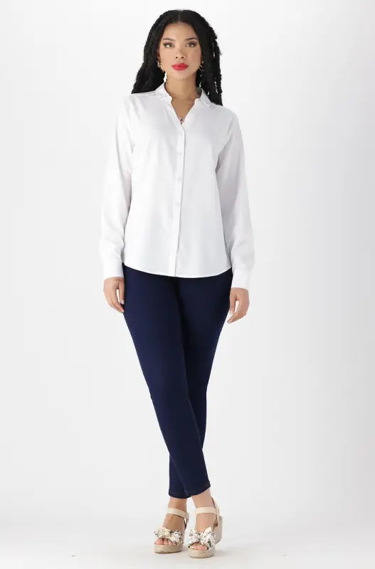 A woman wearing a white collared shirt, navy blue pants, and platform sandals with decorative bows.