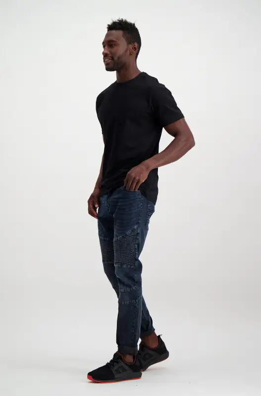 Men’s black short-sleeve t-shirt, dark blue ripped jeans, and black and red athletic shoes.