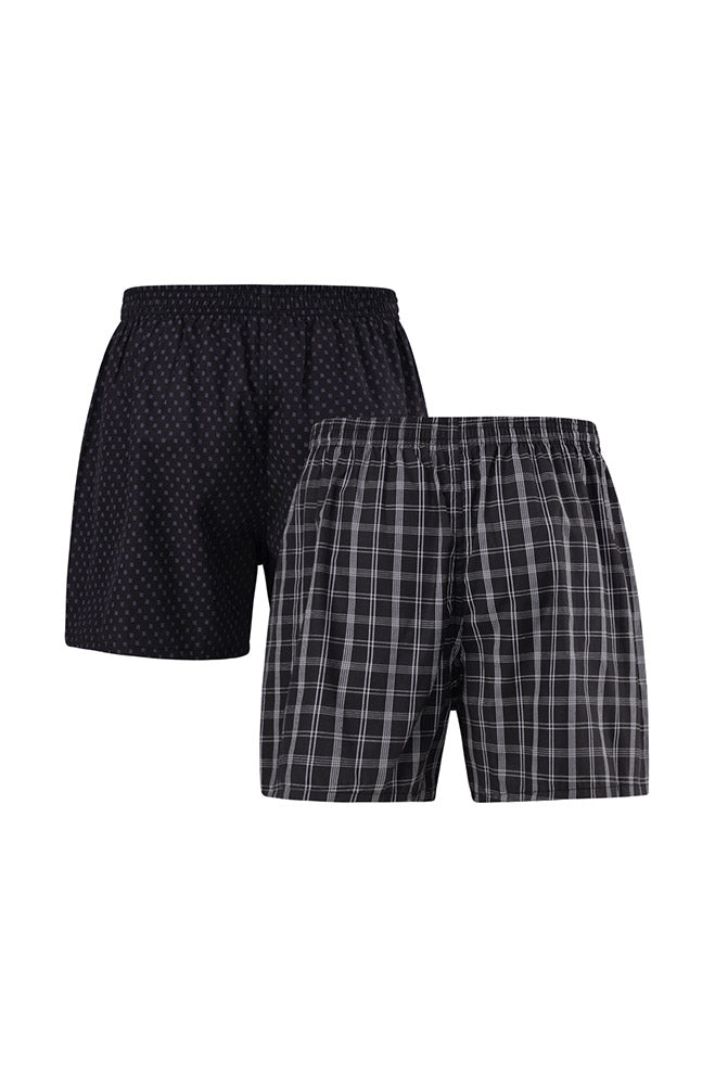 A two-pack of men’s woven boxer shorts, one in black with small polka dots and the other in a black and white plaid pattern.