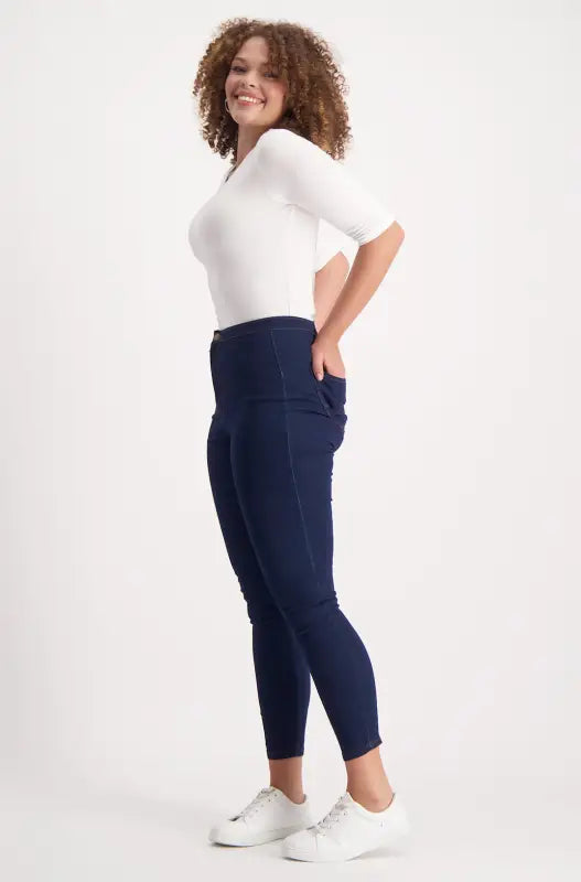 A woman wearing a white t-shirt, dark blue jeans, and white sneakers.