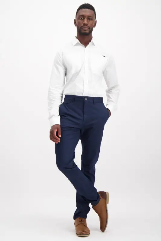 Men’s white long-sleeved dress shirt with navy blue trousers and brown dress shoes.