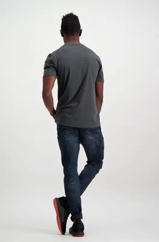Men’s dark gray t-shirt and dark wash jeans with black and red sneakers