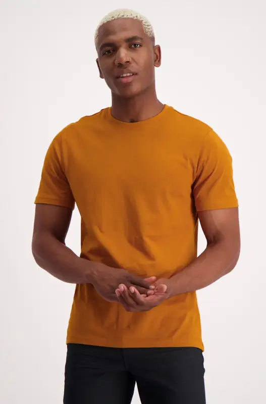 A man wearing a short-sleeved, crew-neck mustard yellow t-shirt.
