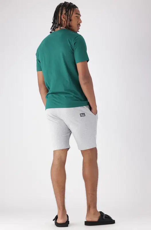 Men’s green short-sleeved t-shirt and light gray shorts set with black sandals.
