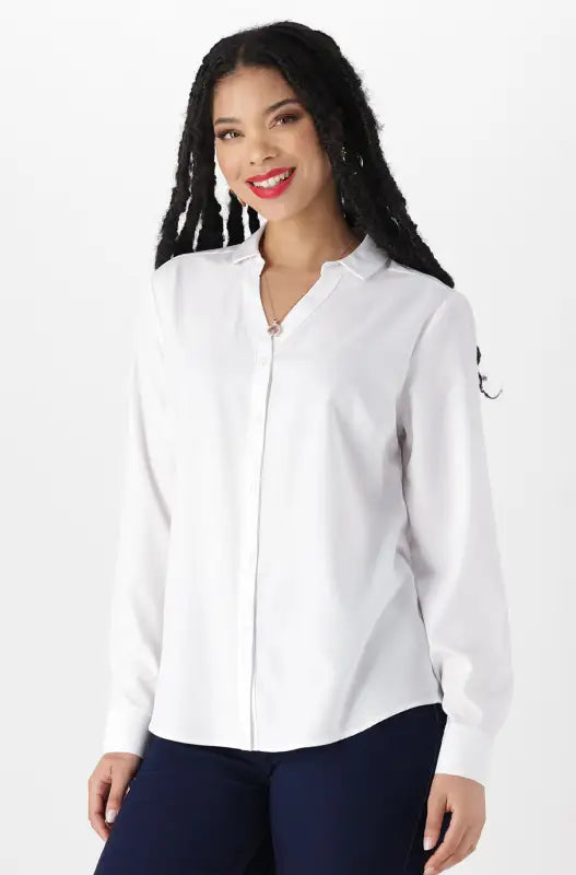 A woman modeling a white long-sleeved collared shirt with a partial front zipper and dark blue pants.