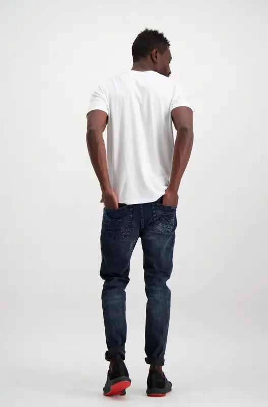 Men’s short-sleeved white t-shirt and dark blue distressed jeans with black and red sneakers